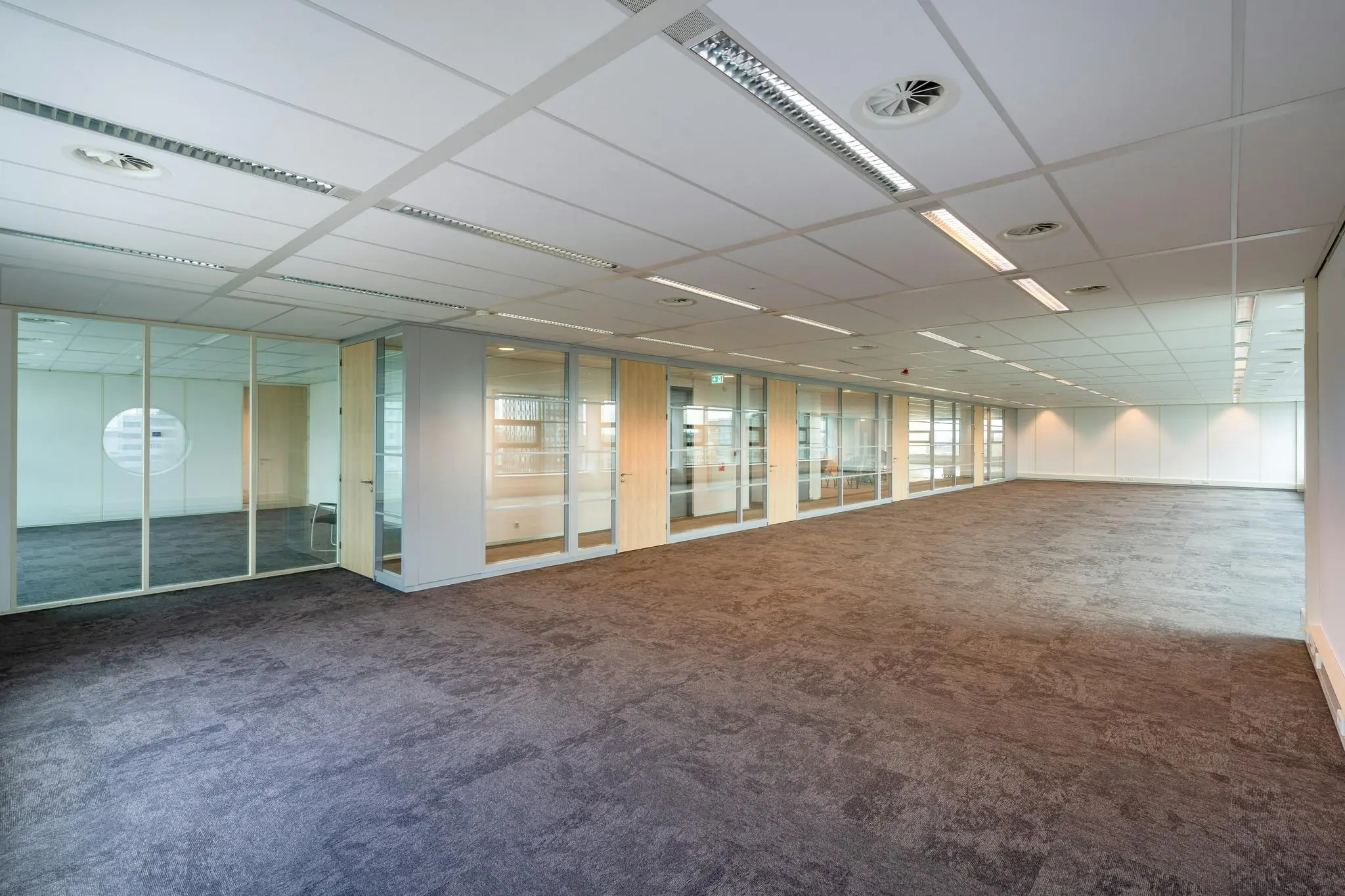 Lege kantoorruimte aan de Fascinatio Boulevard met glazen binnenwanden en systeemplafond.